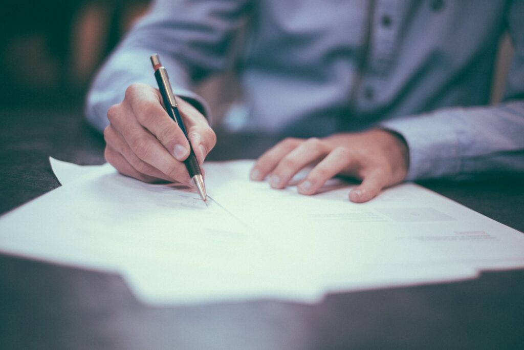 man's hands signing documents on desk
