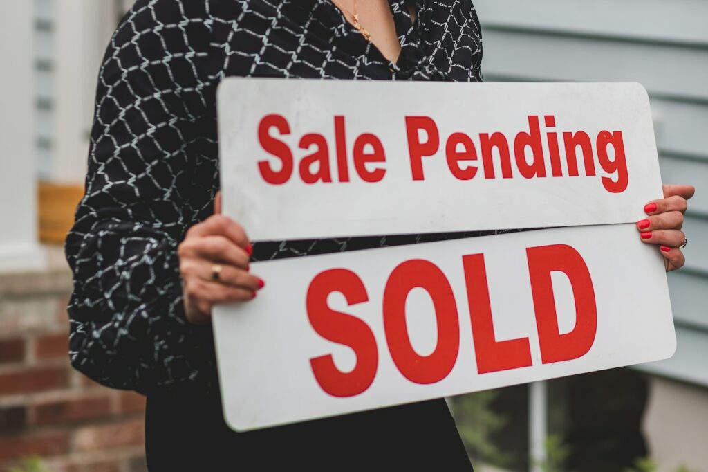 woman holding signs sale pending and sold while waiting for land buyers