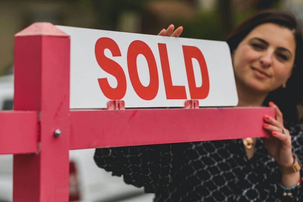 Woman holding sign sold after selling land without a realtor