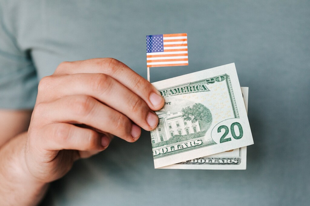 Man's hands holding twenty dollar bill along with American flag symbolizing the way to determine land value