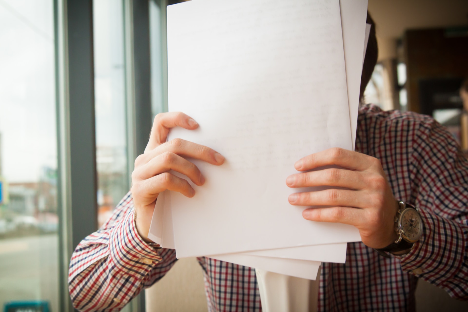 Man's hands holding documents needed to sell land by owner