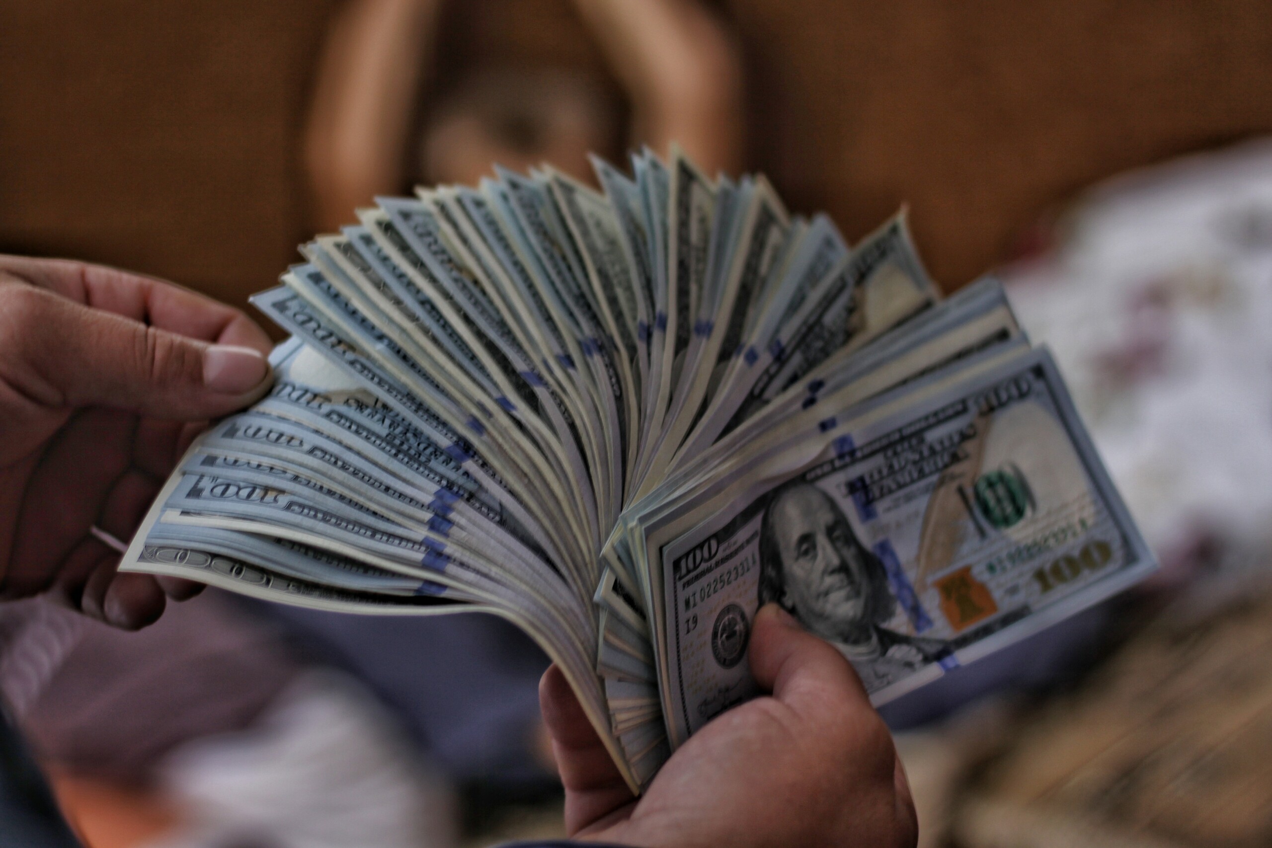 Girl holding $100 bills from selling land for cash